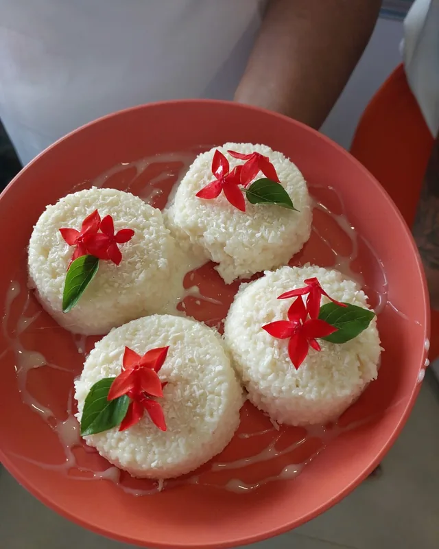 Prato com porções de cuscuz de tapioca decoradas com flores vermelhas.